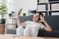 Pretty Asian woman sit on sofa at home enjoy with video call meeting with friend. Woman making content by smartphone at Royalty Free Stock Photo