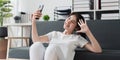 Pretty Asian woman sit on sofa at home enjoy with video call meeting with friend. Woman making content by smartphone at Royalty Free Stock Photo