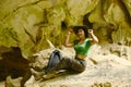 Pretty Asian woman sitting on a rock with happiness and cheerfulness at Tham Hup Pa Tat.