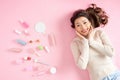 Pretty Asian woman smiling while lying on pink floor with her cosmetic makeup tools. Top view Royalty Free Stock Photo