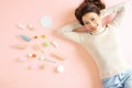 Pretty Asian woman smiling while lying on pink floor with her cosmetic makeup tools. Top view Royalty Free Stock Photo