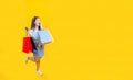 Pretty Asian woman in trendy summer fashion is smiling and holding shopping bag in happiness for discount sale isolated on yellow Royalty Free Stock Photo