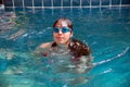 Pretty Asian woman wearing red bikini with waterproof glasses swimming at swimming pool.