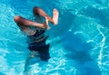 Pretty athletic sun tanned girl making a handstand in a swimming pool on vacation