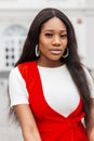 Pretty attractive african young woman in fashionable red-white clothes relaxes outdoors. Fresh portrait black girl fashion model Royalty Free Stock Photo