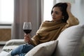 Pretty, attractive, stylish young woman sitting on couch having raised glass with red wine, examine, taste beverage Royalty Free Stock Photo