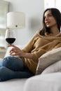 Pretty, attractive, stylish young woman sitting on couch having raised glass with red wine, examine, taste beverage Royalty Free Stock Photo