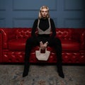 Pretty attractive young blond woman in black stylish clothes in an elegant pearl top with a vintage elegant pearl bag poses on a Royalty Free Stock Photo