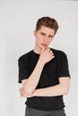 Pretty attractive young man fashion model with hairstyle in black stylish casual t-shirt in vintage jeans posing on a white Royalty Free Stock Photo