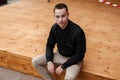 Pretty attractive young man in fashionable clothes is sitting on a vintage wooden terrace outdoors in the spring day. Royalty Free Stock Photo