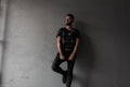 Pretty attractive young man with a fashionable hairstyle and brutal beard in a military stylish shirt, black jeans Royalty Free Stock Photo