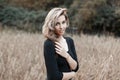 Pretty attractive young woman with blue eyes with a cute smile in a vintage stylish black t-shirt is resting in a field Royalty Free Stock Photo