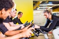 Pretty authentic female instructor with headset in fitness class exercise with group in cycling room Royalty Free Stock Photo