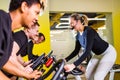 Pretty authentic female instructor with headset in fitness class exercise with group in cycling room Royalty Free Stock Photo