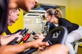 Pretty authentic female instructor with headset in fitness class exercise with group in cycling room Royalty Free Stock Photo