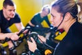 Pretty authentic female instructor with headset in fitness class exercise with group in cycling room Royalty Free Stock Photo