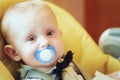 Pretty Baby Boy Sitting In Yellow Seat With Soother