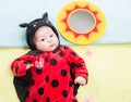 Pretty baby girl, dressed in ladybug costume on green background. Royalty Free Stock Photo