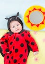 Pretty baby girl, dressed in ladybug costume on green background. Royalty Free Stock Photo