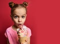 Pretty baby girl kid eating licking big ice cream in waffles cone with raspberry surprised Royalty Free Stock Photo