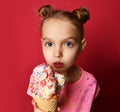 Pretty baby girl kid holding ice cream in waffles cone with raspberry showing surprised Royalty Free Stock Photo