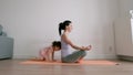 Pretty baby girl playing with her mom while she is doing yoga at home Royalty Free Stock Photo