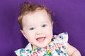 Pretty baby girl on purple blanket in floral summer dress