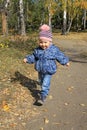 Pretty baby girl walking in autumn park