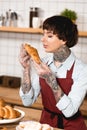 Pretty barista in disposable gloves holding delicious croissant. Royalty Free Stock Photo