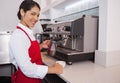 Pretty barista pouring milk into cup of coffee smiling at camera Royalty Free Stock Photo