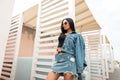 Pretty beautiful young hipster woman in a stylish denim jacket in a trendy black top in a vintage jeans torn skirt in sunglasses