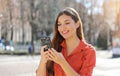 Pretty beautiful young woman with long hair messaging on the smart phone in city street. Smiling girl having smart phone Royalty Free Stock Photo