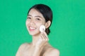 Pretty beauty young Asian woman cleaning her face with cotton pad over green isolated background. Healthy skin and cosmetics Royalty Free Stock Photo