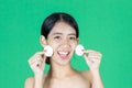 Pretty beauty young Asian woman cleaning her face with cotton pad over green isolated background. Healthy skin and cosmetics Royalty Free Stock Photo