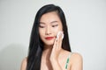 Pretty beauty young Asian woman cleaning her face with cotton pad over white isolated background. Healthy skin and cosmetics Royalty Free Stock Photo