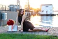 Pretty birthday girl with brown hair in little black dress sitting on the wooden footpath at sunset Royalty Free Stock Photo
