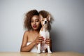 Pretty black american female with afro hair hugging her puppy basenji dog. Love between dog and owner. Isolated on white Royalty Free Stock Photo