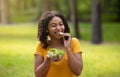 Pretty black girl eating fresh vegetable salad and winking at green park on summer day Royalty Free Stock Photo