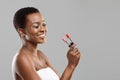 Pretty black girl holding and choosing between red and pink lipstick Royalty Free Stock Photo