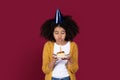 Pretty black teen girl having birthday party, blowing candle Royalty Free Stock Photo