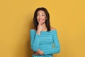 Pretty black woman in blue shirt thinking and looking up aside on colorful yellow background Royalty Free Stock Photo