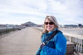 Pretty blond adult female stands on the Tybee Island pier, bundled up in a winter jacket Royalty Free Stock Photo