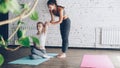 Female yoga student is learning arm twists in cow face position from friendly cheerful instructor on personal training