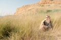 Pretty blond girl sitting on field with dry grass.