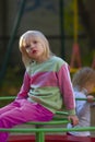 Pretty blond toddler girl wearing fancy sport costume sitting on carusel on the playground Royalty Free Stock Photo