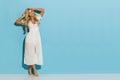 Pretty Blond Woman In White Summer Dress Is Standing Against Blue Wall Royalty Free Stock Photo
