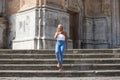 Pretty blonde adult woman dressed in jeans and white top having fun posing for photos on the steps of the cathedral in Cadiz, Royalty Free Stock Photo