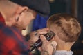 Caucasian boy getting haircut in barbershop indoor