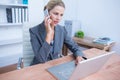 Pretty blonde businesswoman phoning and using her laptop Royalty Free Stock Photo