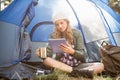 Pretty blonde camper using tablet and holding cup